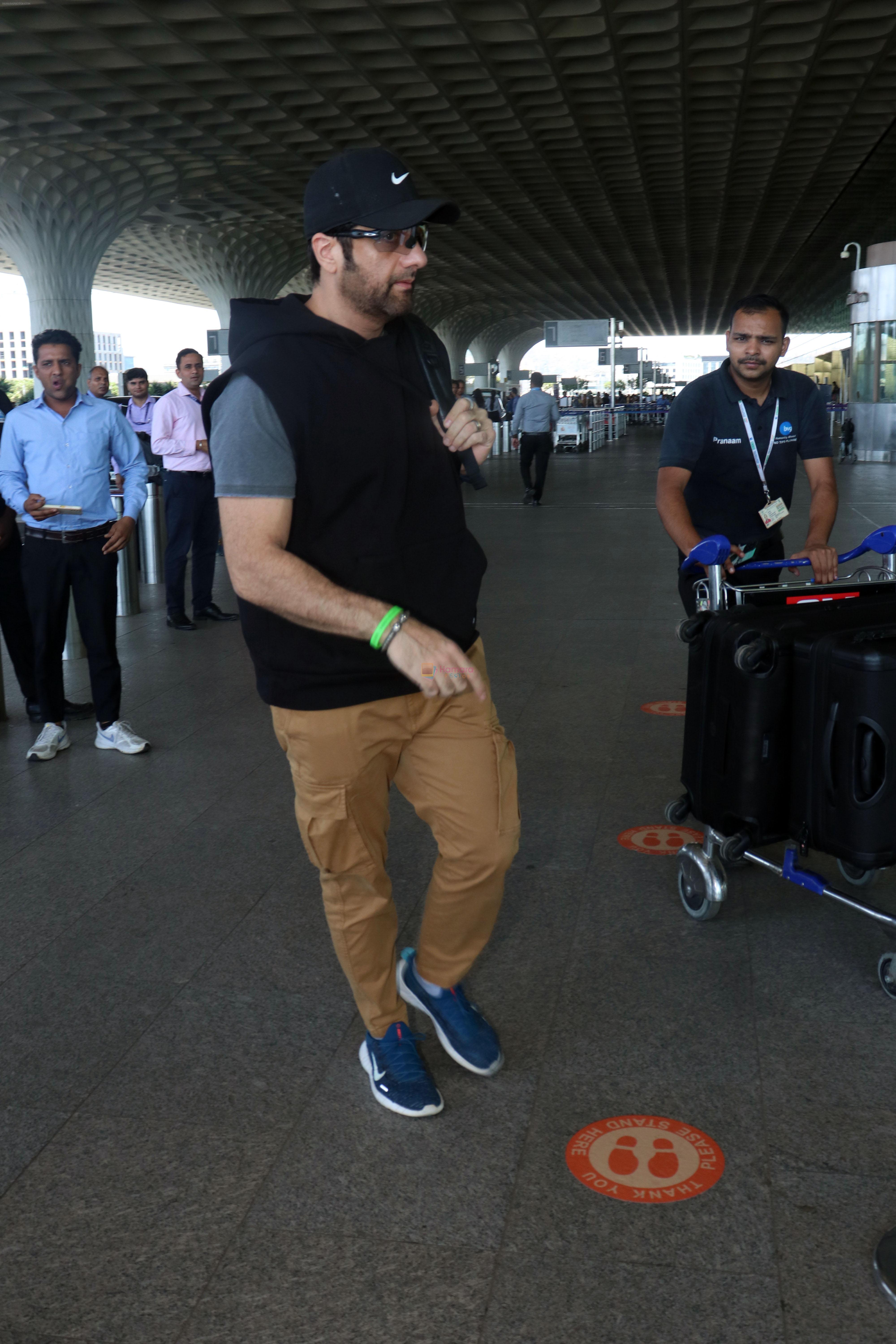 Fardeen Khan wearing sunglasses, black shirt, khaki pants, blue nike shoes and black Nike hat