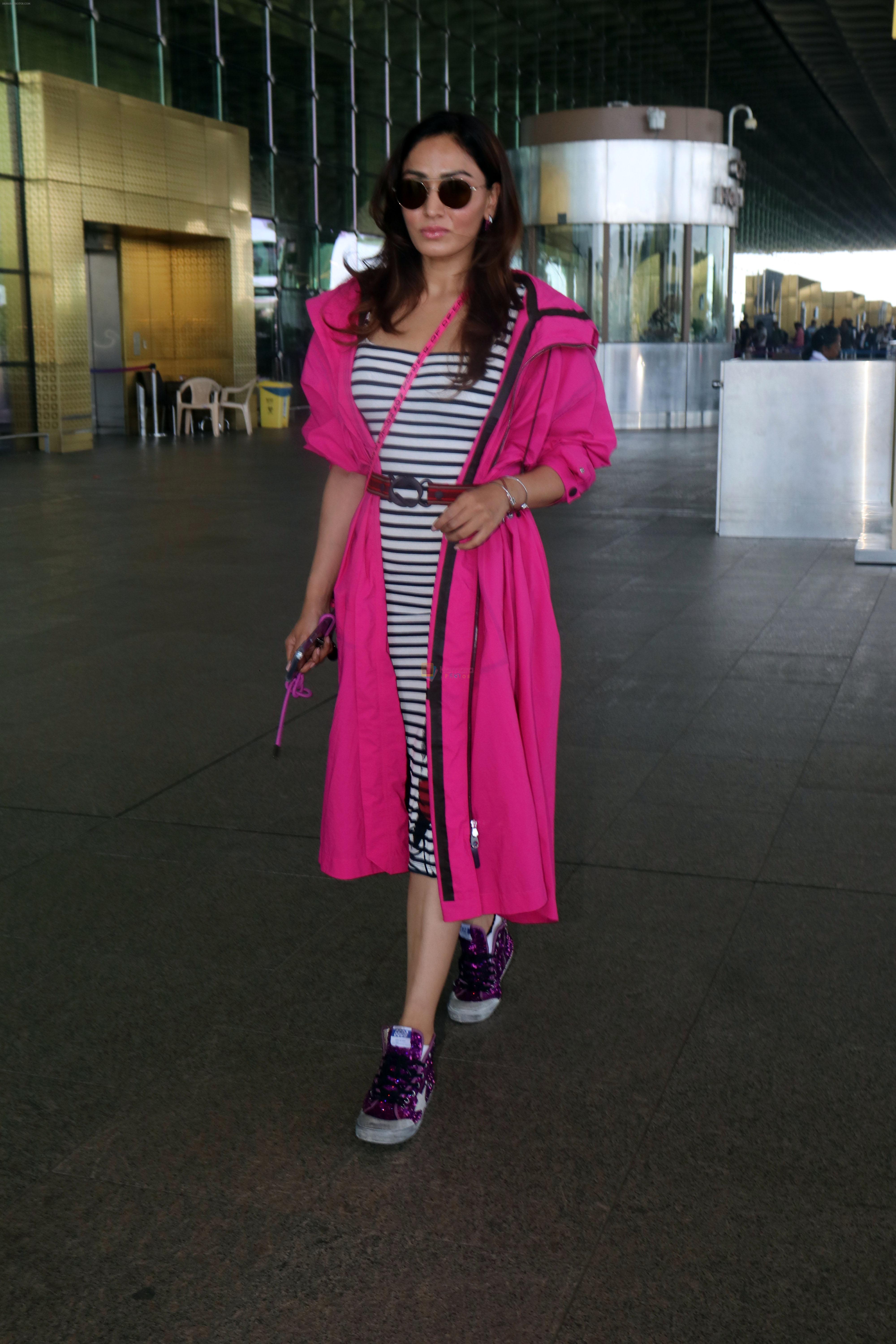 Khushali Kumar wearing a stylish pink coat and sunglasses in a pair of purple high top sneakers