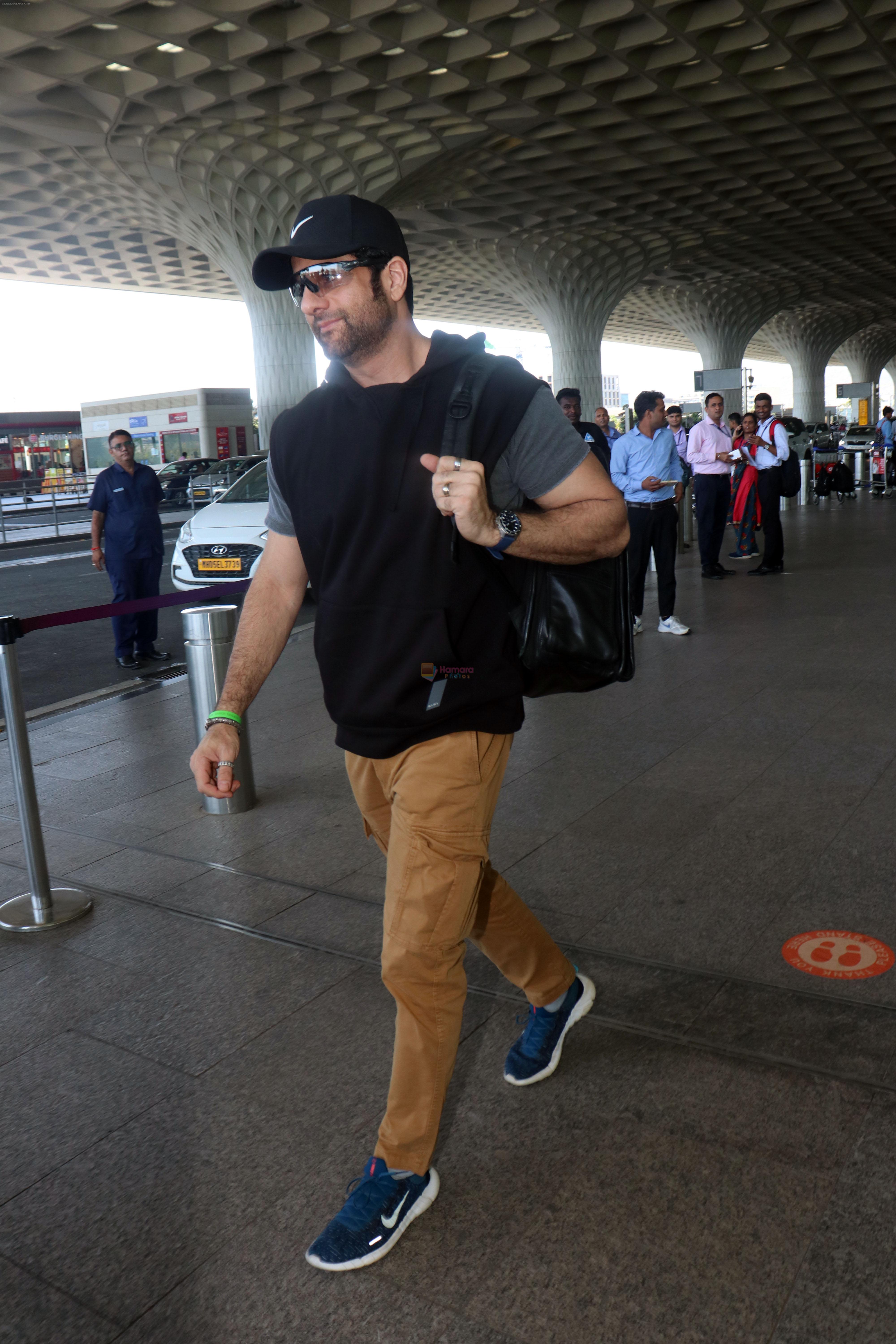 Fardeen Khan wearing sunglasses, black shirt, khaki pants, blue nike shoes and black Nike hat