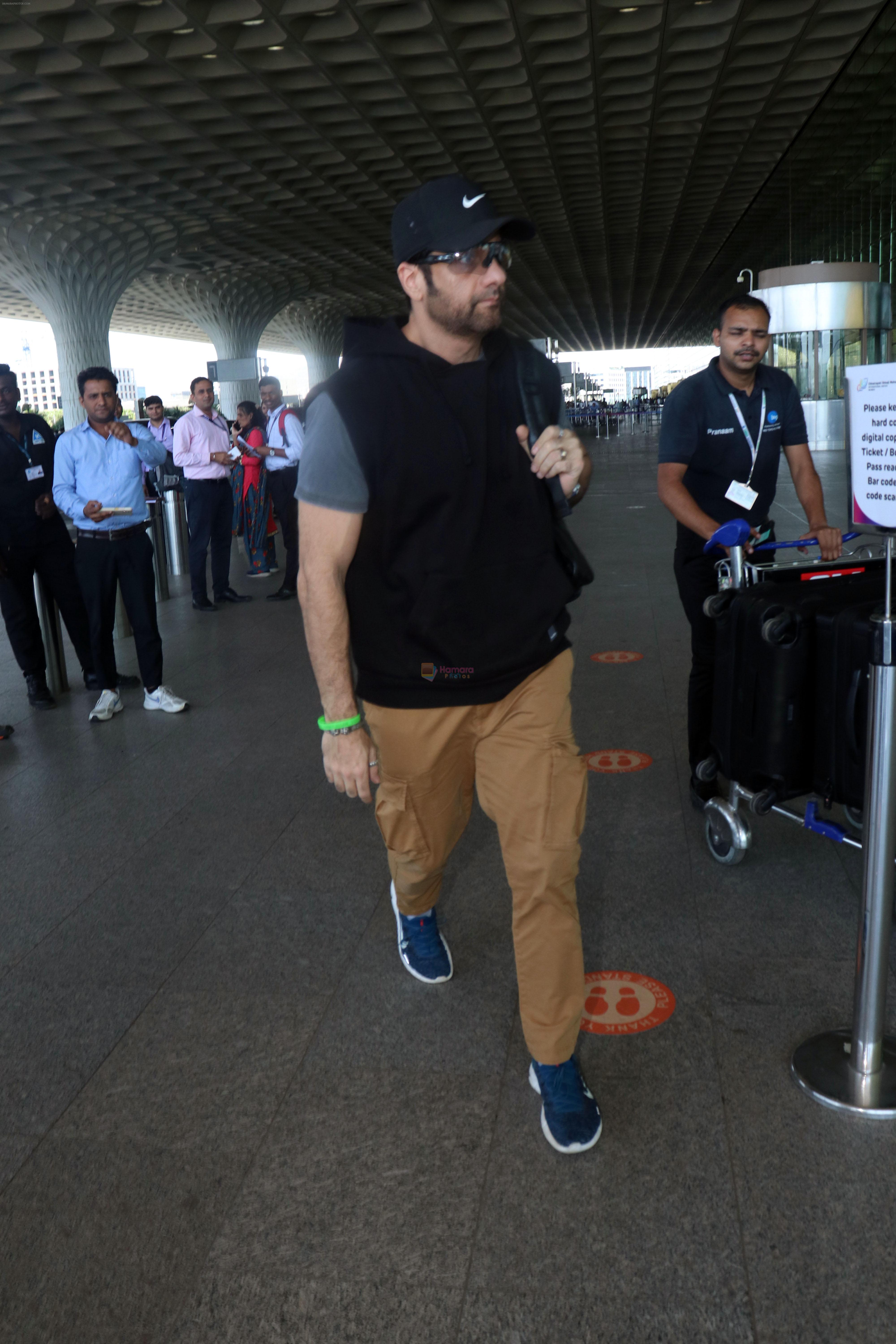 Fardeen Khan wearing sunglasses, black shirt, khaki pants, blue nike shoes and black Nike hat