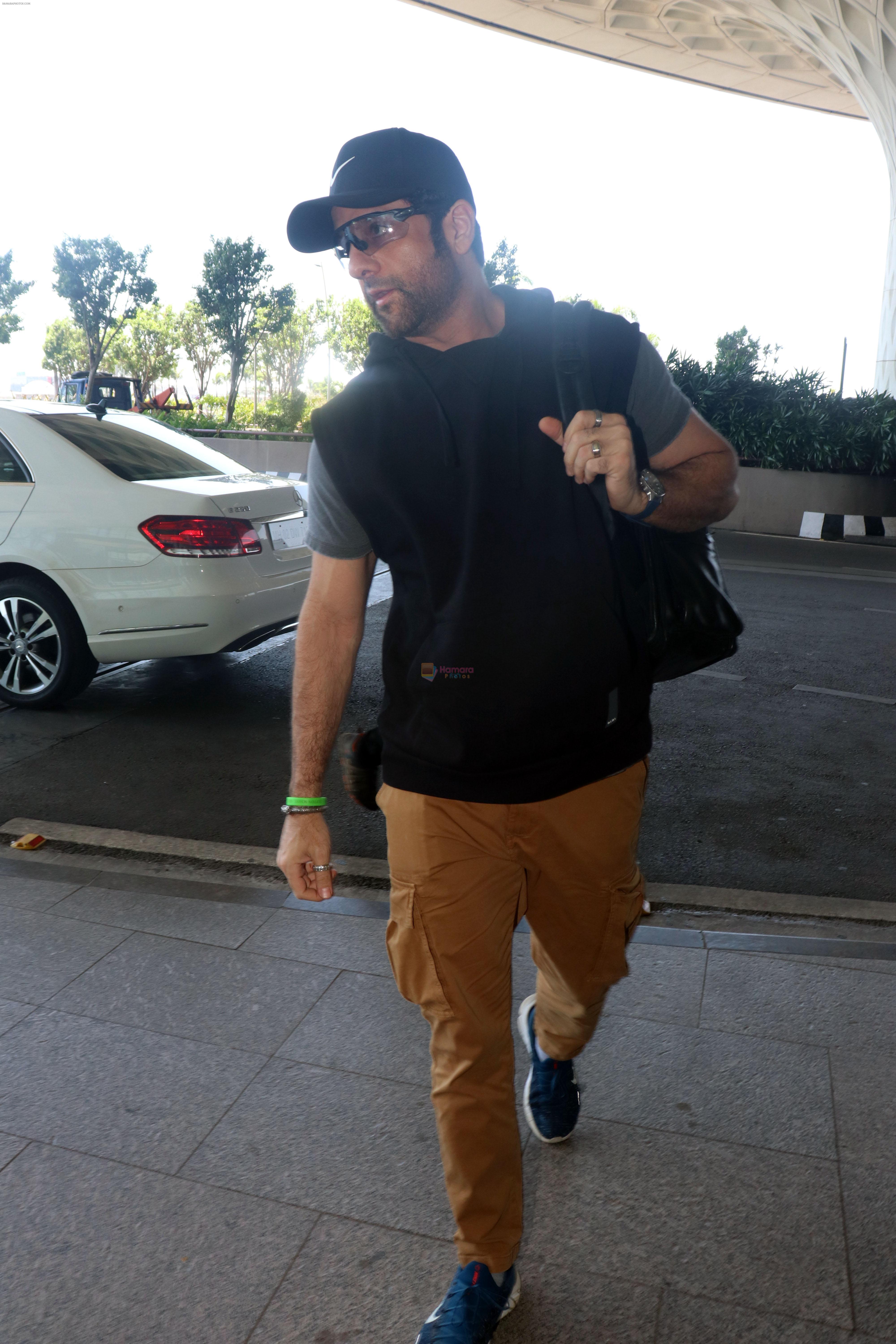 Fardeen Khan wearing sunglasses, black shirt, khaki pants, blue nike shoes and black Nike hat