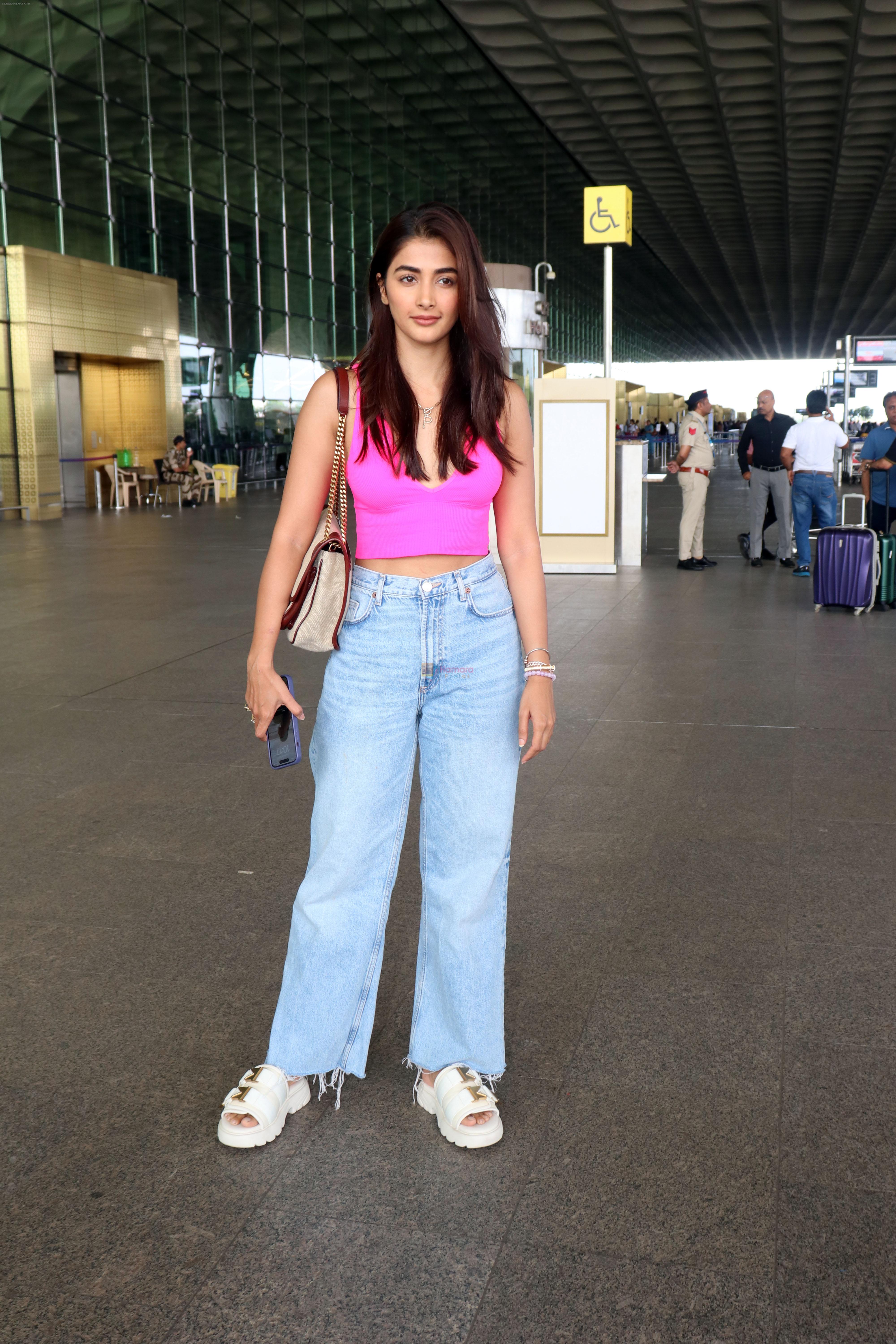 Pooja Hegde in a pink sleeveless top and blue jeans holding a Saint Laurent Niki Medium Linen shoulder bag and Bottega Veneta Flash leather trimmed stretch slides