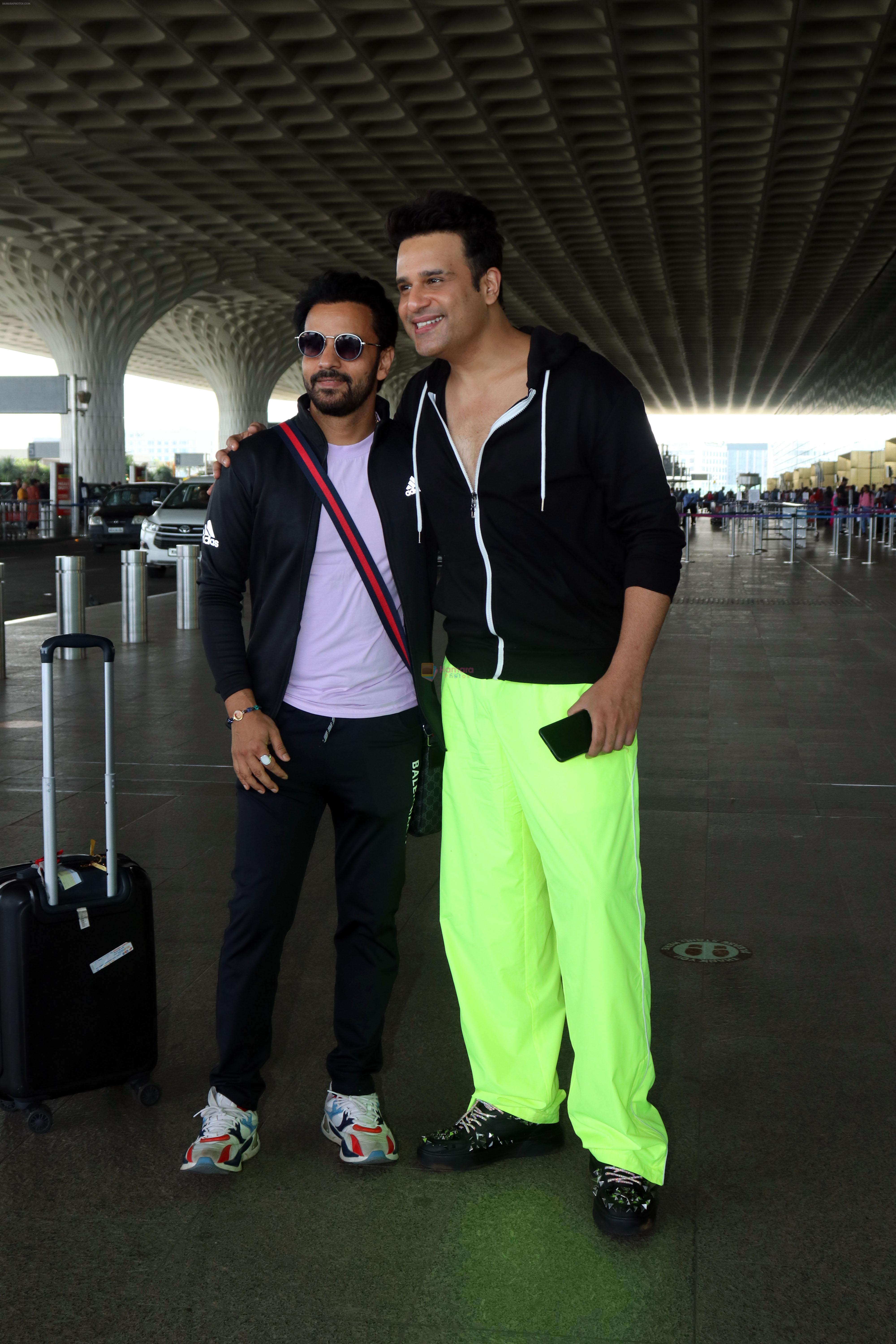 Krushna Abhishek in a black laced coat and fluorescent green pants and black sneakers