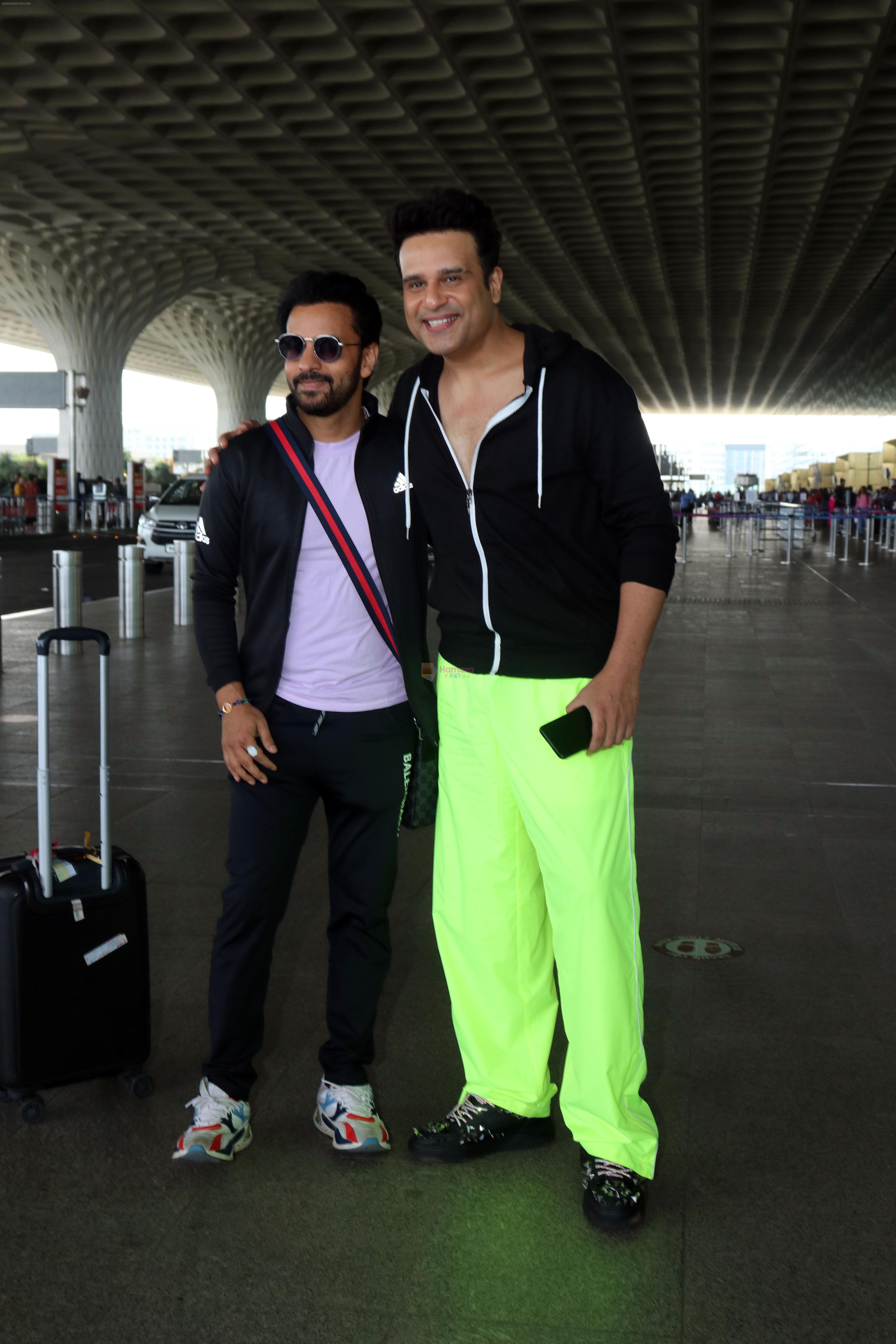 Krushna Abhishek in a black laced coat and fluorescent green pants and black sneakers