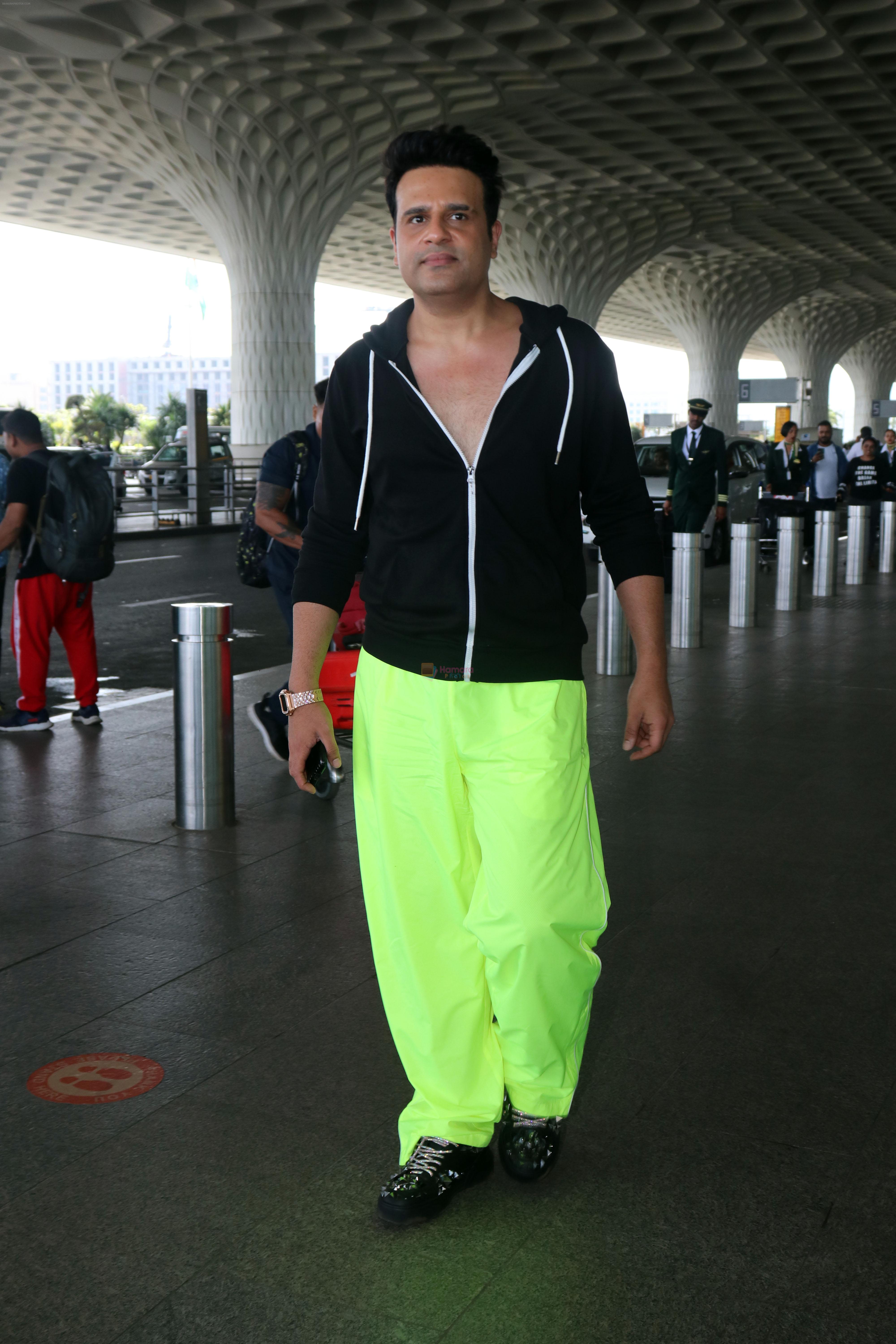 Krushna Abhishek in a black laced coat and fluorescent green pants and black sneakers