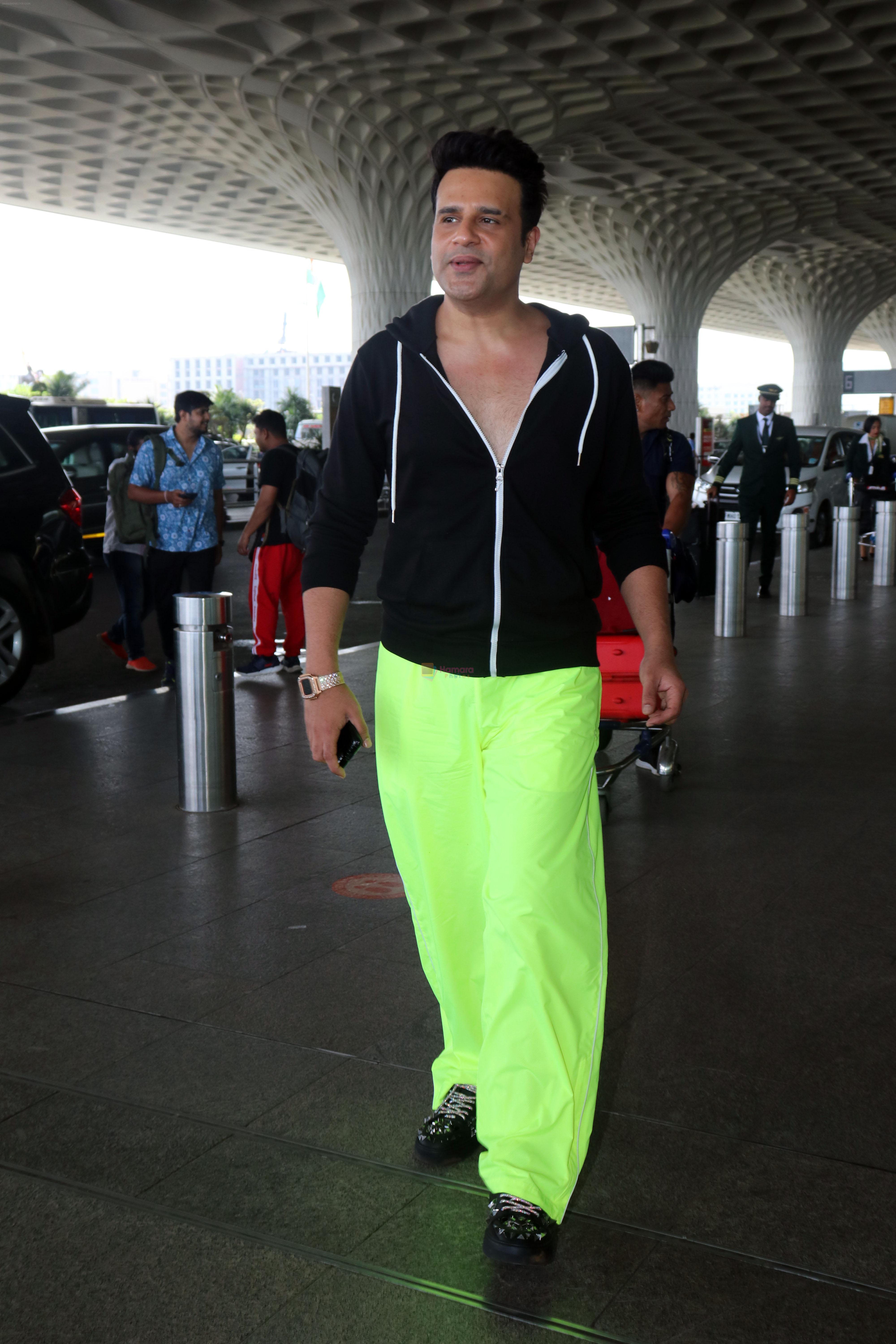 Krushna Abhishek in a black laced coat and fluorescent green pants and black sneakers