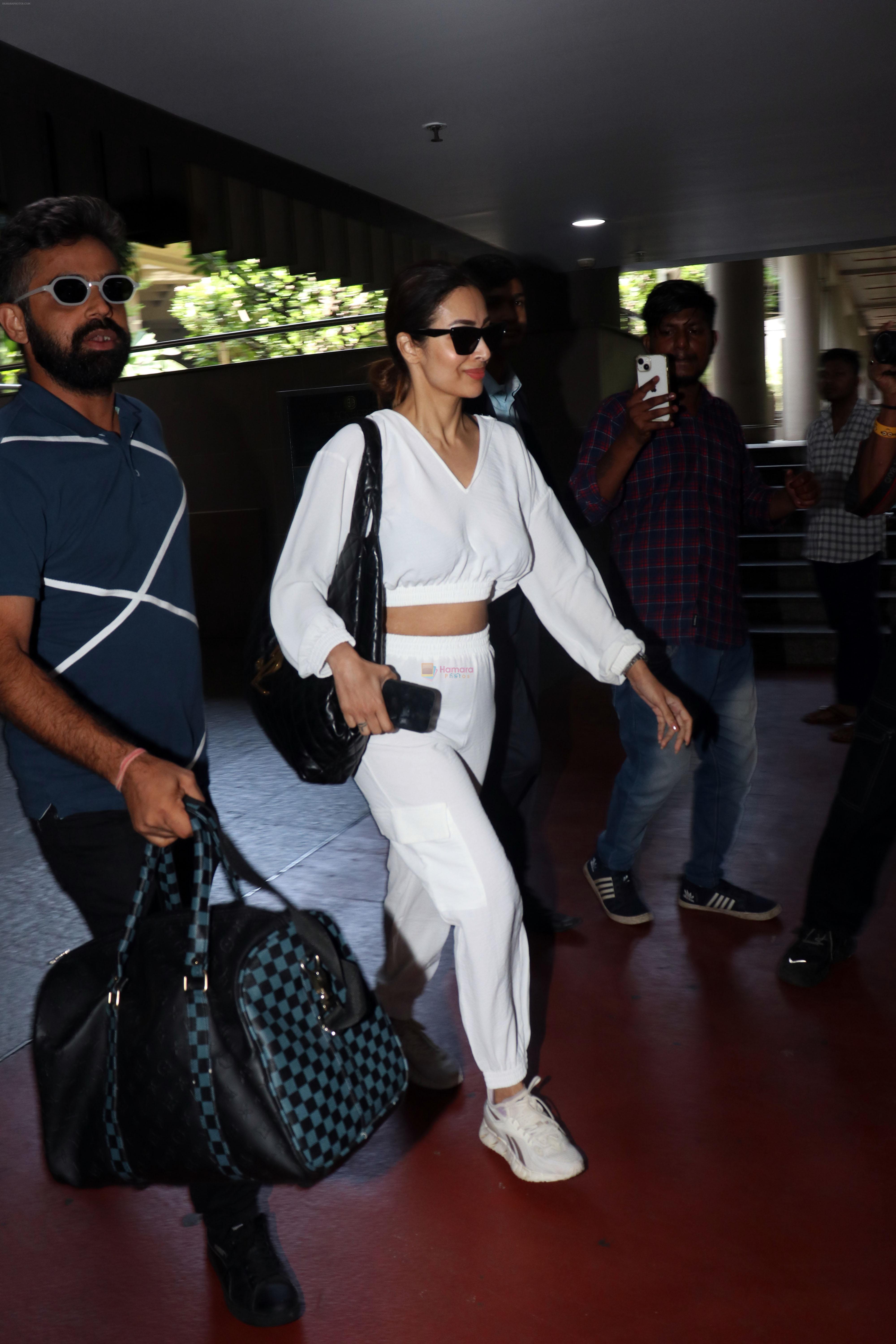 Malaika Arora in white wearing dark glasses white sneakers and holding black Chanel Bag