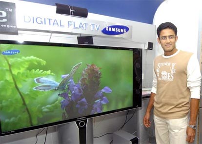 Anil Kumble stands next to a Samsung projection television at a Samsung showroom
