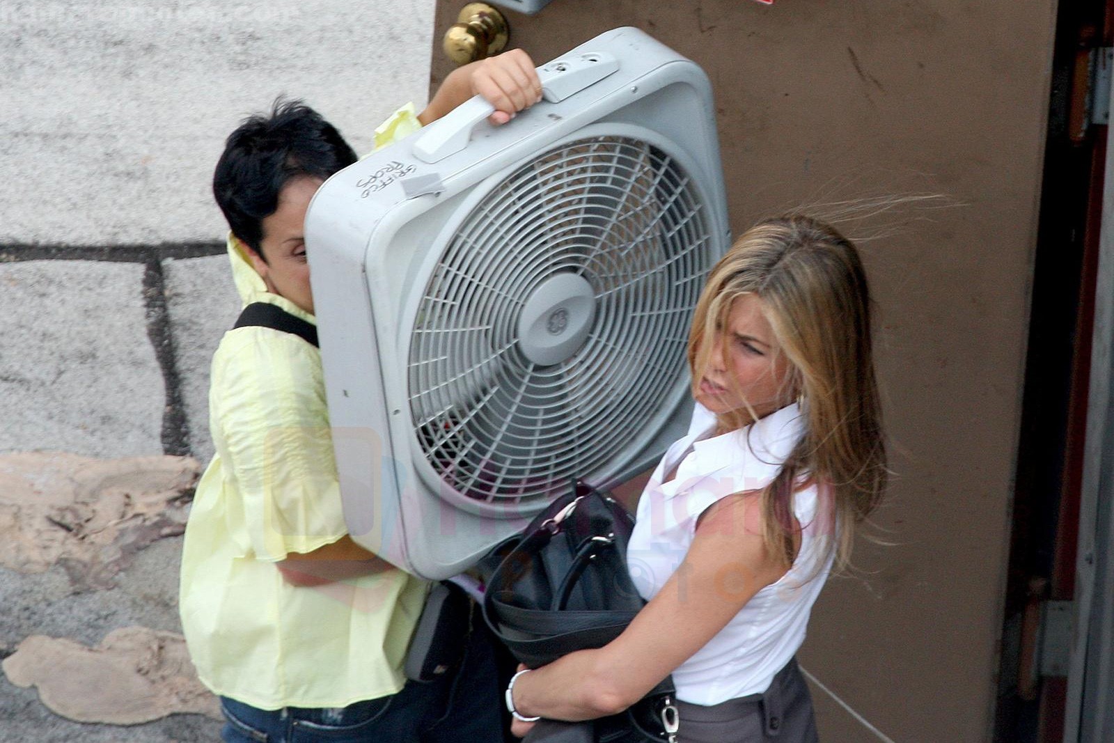 Jennifer Aniston keeps cool, by having a assistant hold up a huge fan in front of her, while on the set of her new film on 22.08.09 