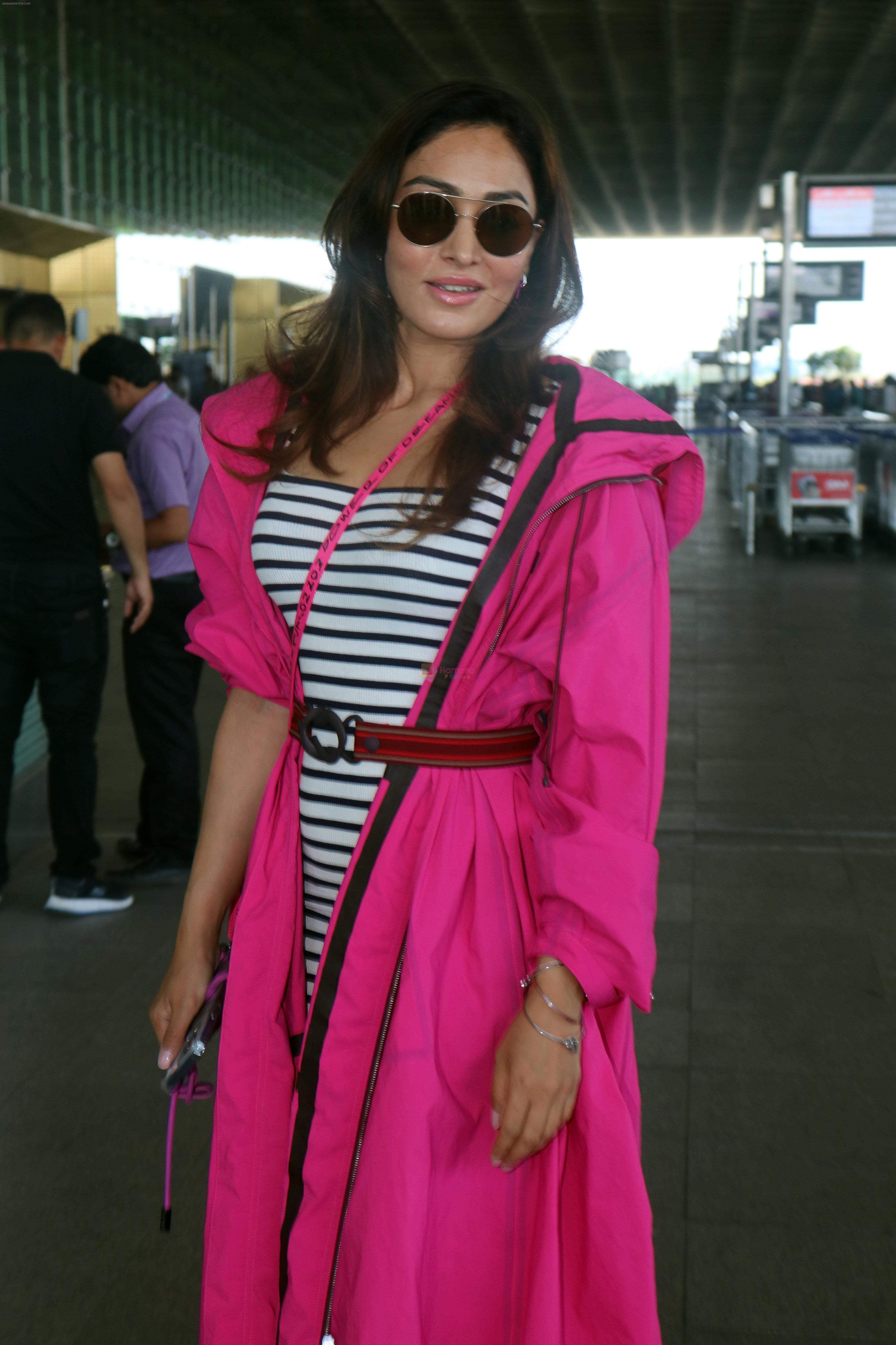 Khushali Kumar wearing a stylish pink coat and sunglasses in a pair of purple high top sneakers