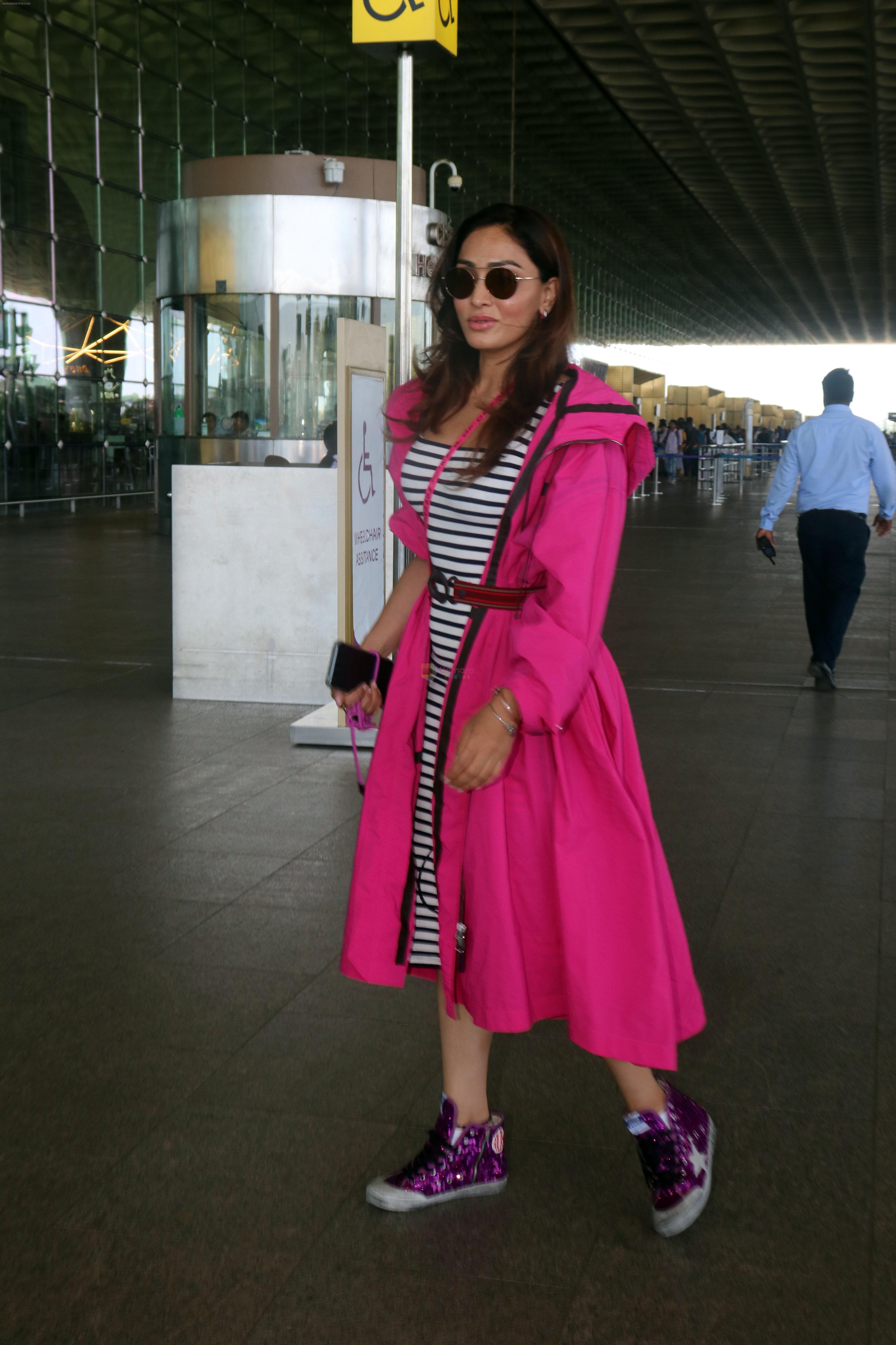 Khushali Kumar wearing a stylish pink coat and sunglasses in a pair of purple high top sneakers