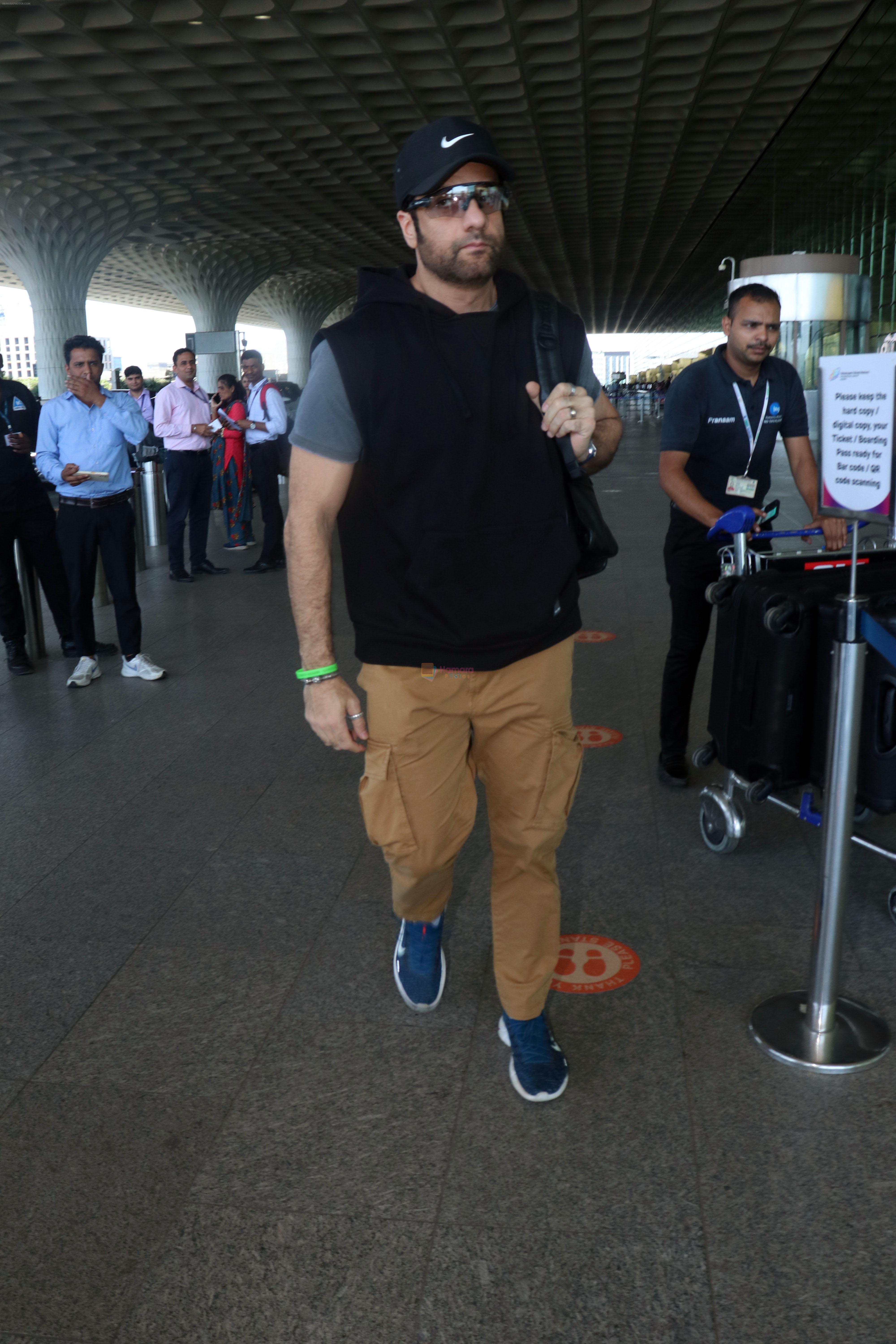 Fardeen Khan wearing sunglasses, black shirt, khaki pants, blue nike shoes and black Nike hat