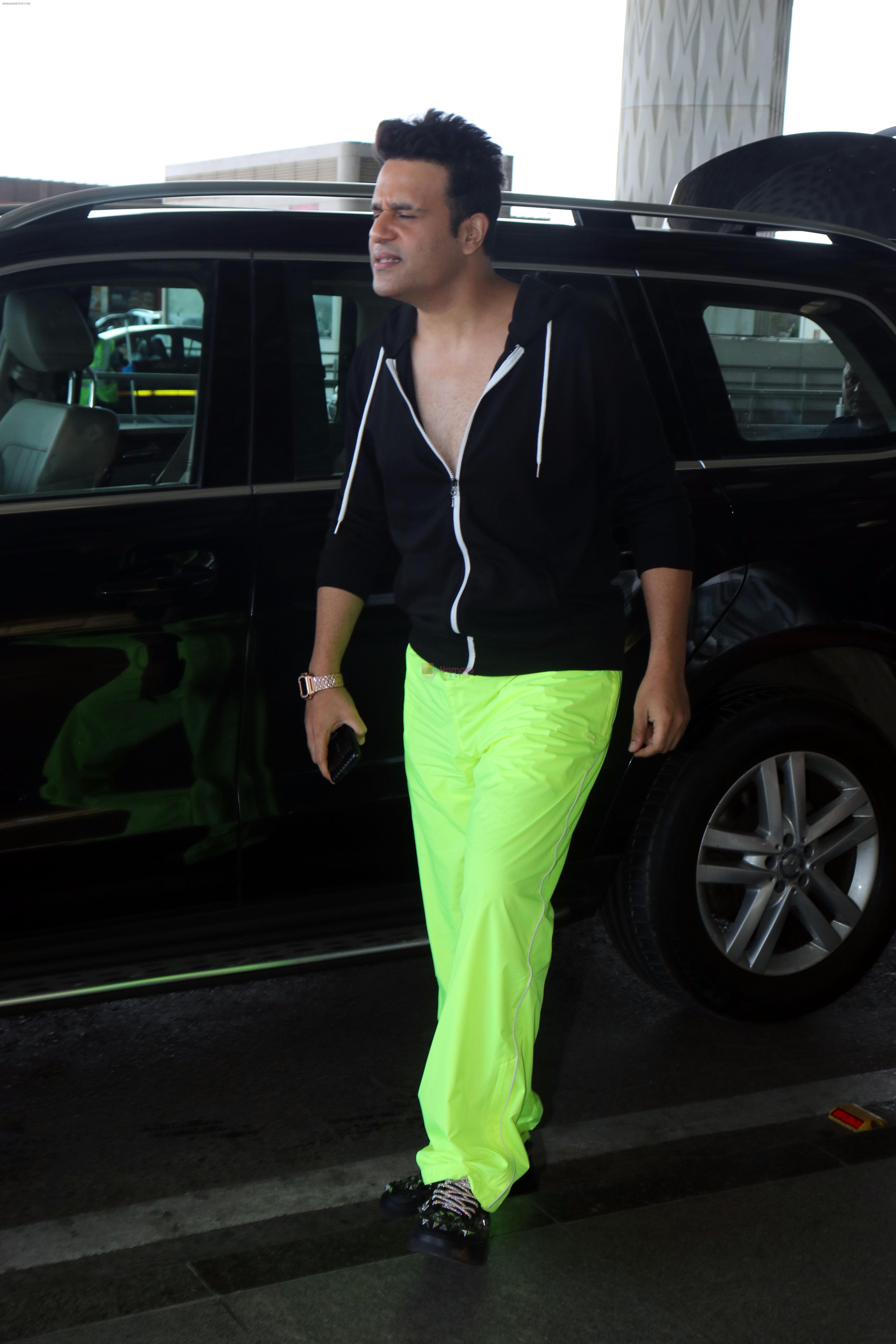 Krushna Abhishek in a black laced coat and fluorescent green pants and black sneakers