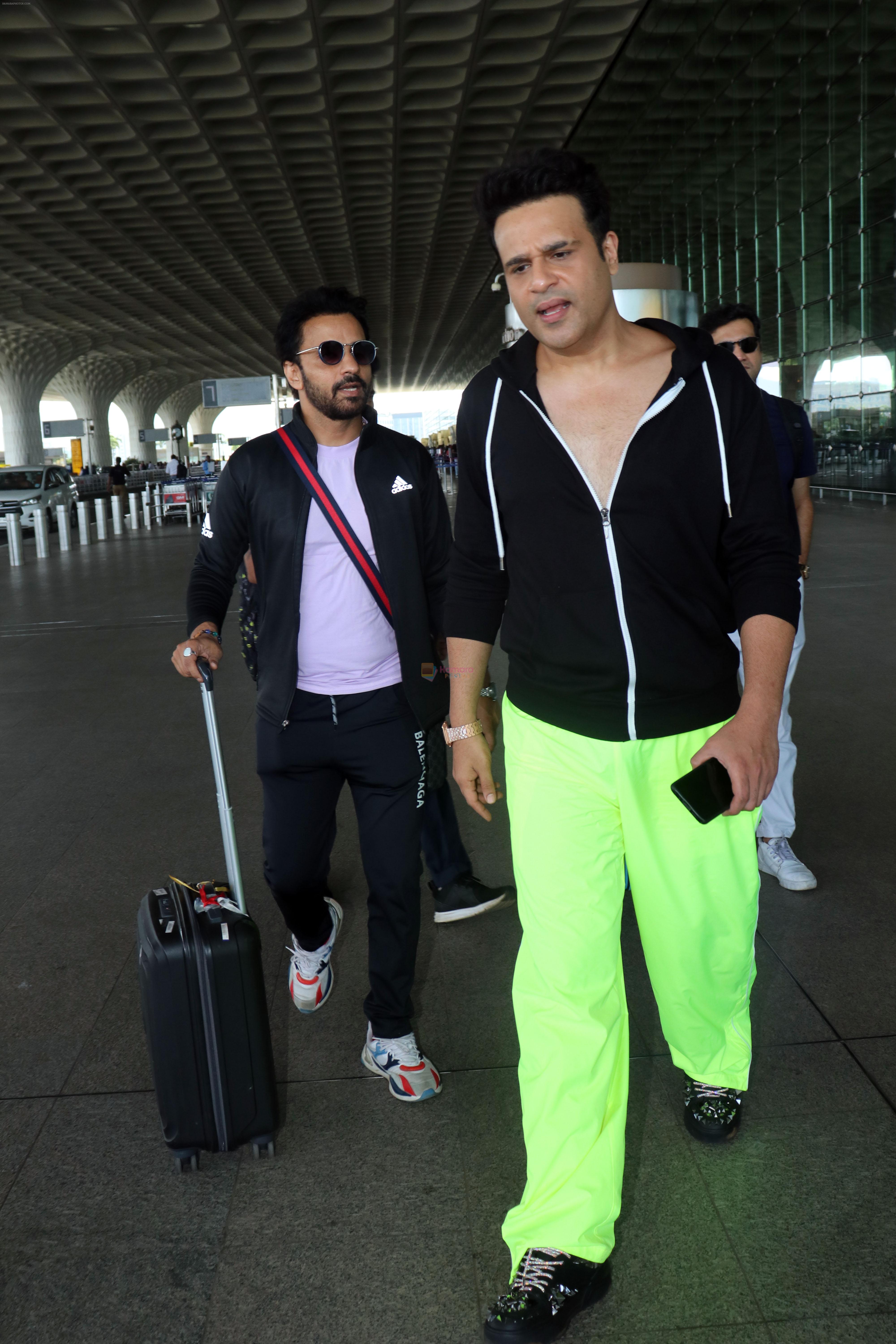 Krushna Abhishek in a black laced coat and fluorescent green pants and black sneakers