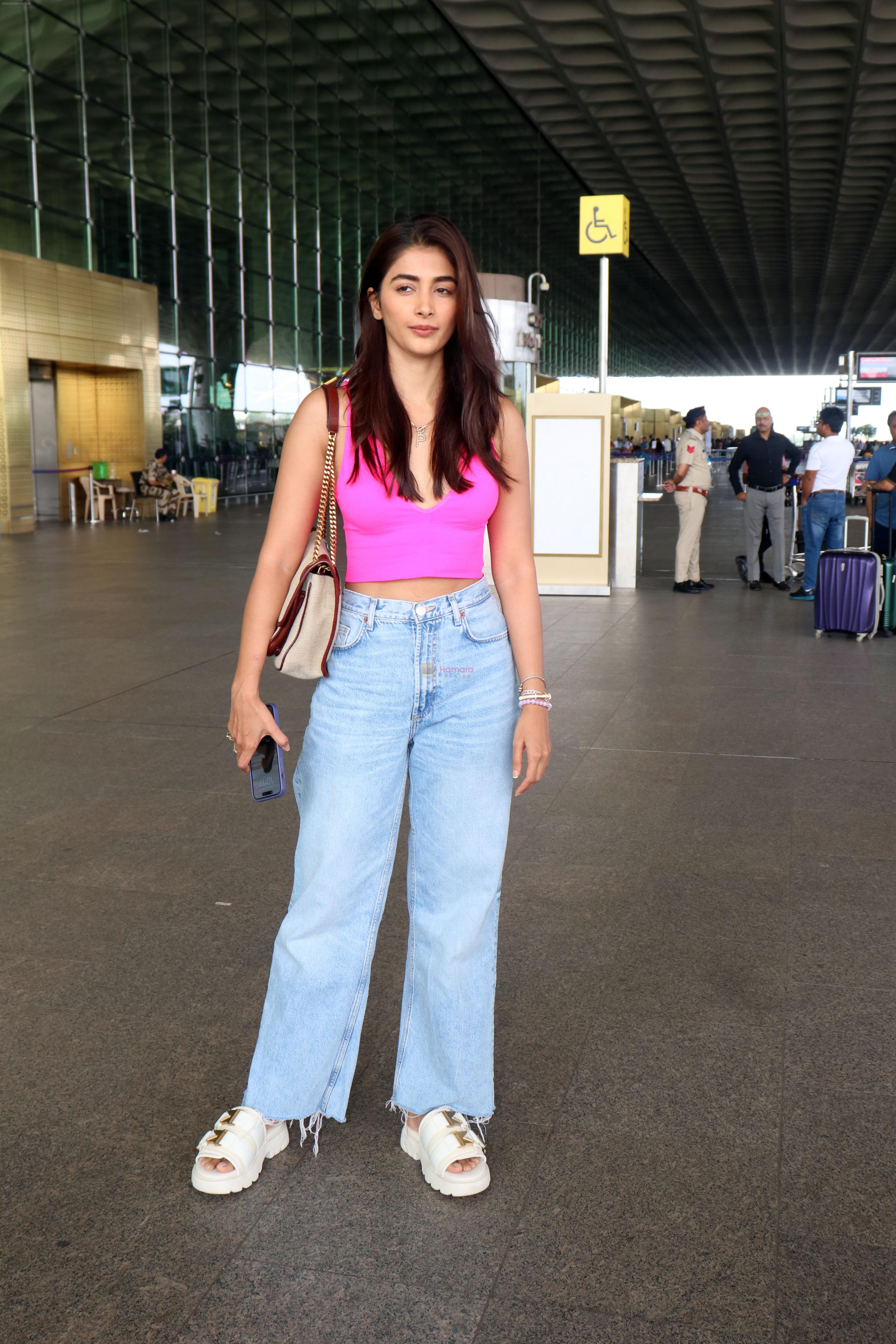 Pooja Hegde in a pink sleeveless top and blue jeans holding a Saint Laurent Niki Medium Linen shoulder bag and Bottega Veneta Flash leather trimmed stretch slides